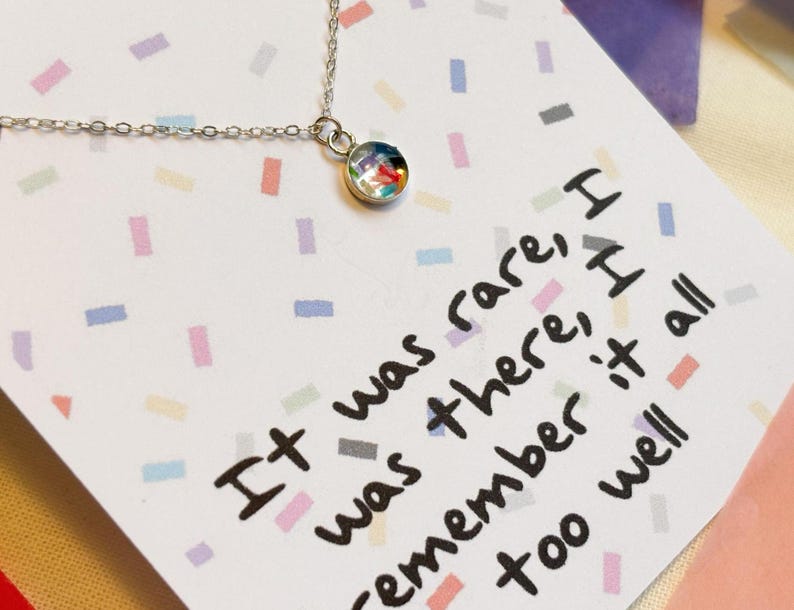 May include: A silver necklace with a small round pendant featuring a colorful confetti design. The necklace comes with a card that reads "It was rare, I was there, I remember it all too well."