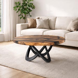 May include: A round coffee table with a dark wood top and black base. The tabletop features a natural wood grain pattern with dark resin accents. The base has a unique, intertwined design.
