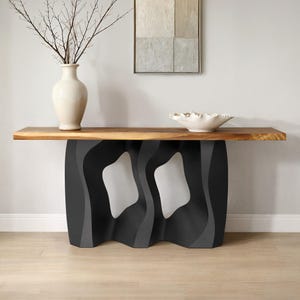 May include: A modern console table with a live edge wooden top and a black, gray, and white wavy base. A white vase with branches and a white bowl are on the table. The table is set against a neutral wall with artwork.