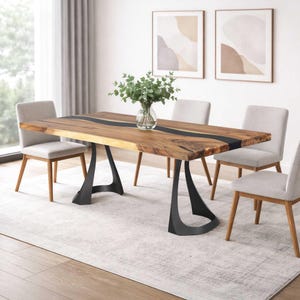 May include: A wooden dining table with a black resin river design, supported by black metal legs. Four light grey upholstered chairs surround the table. A vase of greenery sits in the centre. Two abstract art prints hang on the wall.