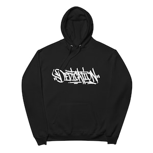 May include: Black hooded sweatshirt with the word "DEDICATION" in white graffiti-style lettering across the chest. The hoodie has a drawstring and a front pocket. The fabric appears to be a soft, comfortable material.