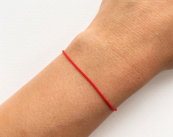 Puede incluir: Un brazalete sencillo de cuerda roja usado en la muñeca.
