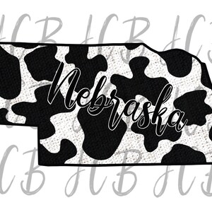 May include: A black and white cow print design fills the outline of the state of Nebraska. The word "Nebraska" is written in a cursive font across the center of the state outline.
