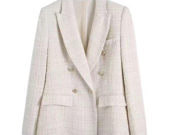 May include: A light-colored double-breasted blazer with gold-colored buttons. The blazer has a textured fabric and two front pockets. The lapels are notched, and the blazer is fully lined. A classic and versatile piece of outerwear.