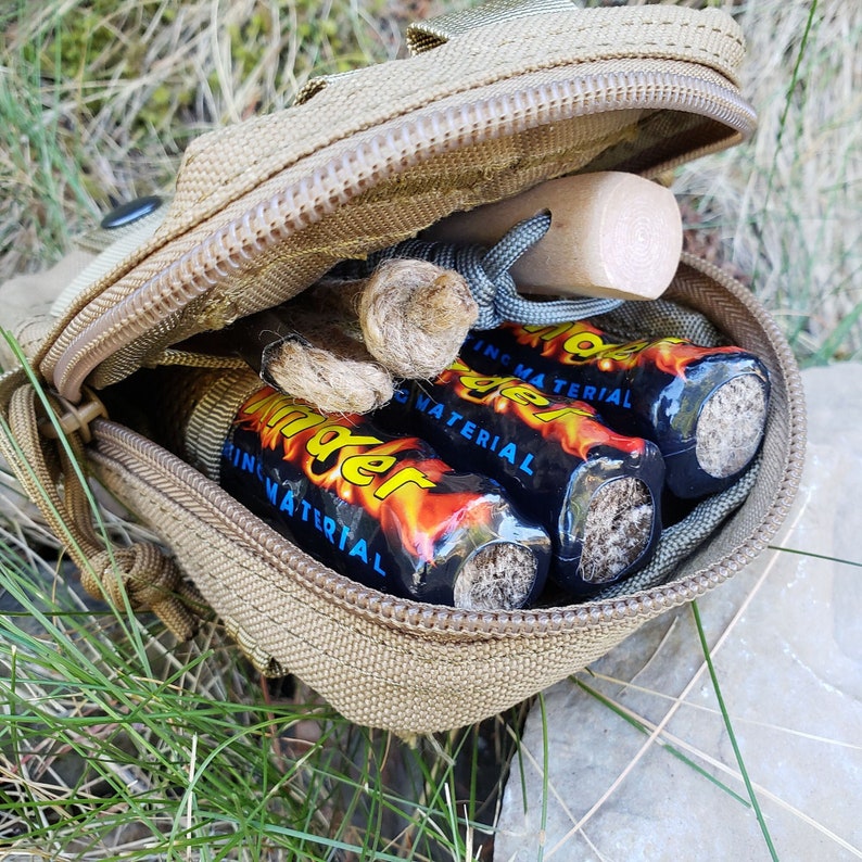 May include: A tan zippered pouch with a brown wooden stick and three fire starters inside. The fire starters are black with a red and blue flame design and the text "Fire Starter" printed on them.