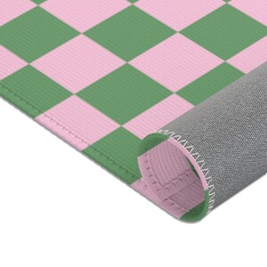 Puede incluir: Una alfombra a cuadros rosa y verde con un respaldo gris. La alfombra est&aacute; enrollada, mostrando el respaldo gris y el patr&oacute;n de cuadros rosa y verde.