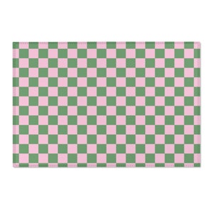 Puede incluir: Un camino de mesa a cuadros rosa y verde. El camino de mesa tiene un patr&oacute;n cuadrado con cuadros rosas y verdes alternos.