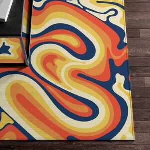 May include: Abstract rug with a swirling pattern in shades of orange, yellow, and blue. The rug has a cream-colored background.