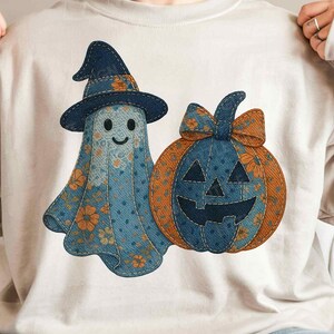 Könnte beinhalten: Beiges Sweatshirt mit Halloween-Design. Das Design zeigt einen freundlichen Geist mit Hexenhut und einen Kürbis, beide aus blauem Denim mit orangefarbenen Blumenmustern. Der Geist hat ein lächelndes Gesicht.