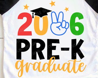 May include: White and black raglan sleeve t-shirt with a colorful graphic. The graphic reads "2026 Pre-K Graduate" with a graduation cap over the zero. The numbers and letters are in red, orange, blue, and green.
