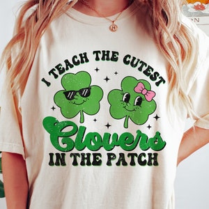 Może przedstawiać: Biała koszulka z zielonym wzorem koniczyny i tekstem "Uczę najsłodszych koniczynek na łące".