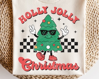 May include: A white t-shirt with a red and green graphic of a cartoon Christmas tree wearing sunglasses and the text "Holly Jolly Christmas".