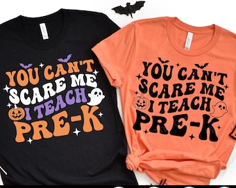 Può includere: Due magliette a tema Halloween con il testo "You can't scare me I teach Pre-K" in bianco e nero con un accento viola. Una maglietta è nera con accenti arancioni e bianchi, e l'altra è arancione con accenti neri e bianchi.