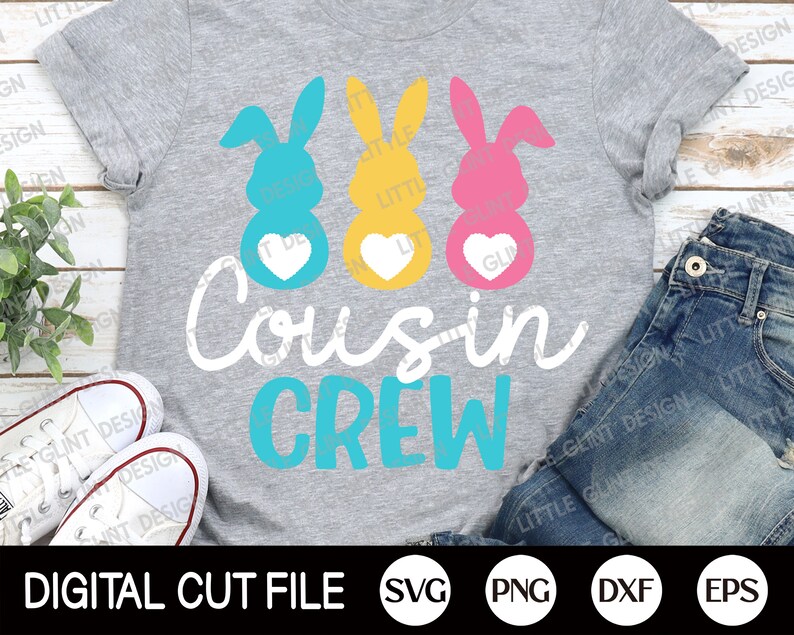 May include: A grey t-shirt with a design of three Easter bunny silhouettes with hearts. The bunnies are blue, yellow, and pink. The text "Cousin Crew" is written in white and blue.