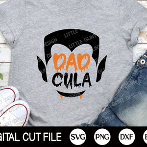 May include: A grey t-shirt with a black silhouette of a vampire with dripping orange text that reads "Dad Cula".