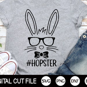 以下が含まれることがあります： 黒い眼鏡と蝶ネクタイをつけた黒いウサギが描かれた灰色のTシャツ。ウサギの下には「#HOPSTER」という文字が書かれています。このTシャツは、SVG、PNG、DXF、EPS形式で利用可能なデジタルカットファイルです。