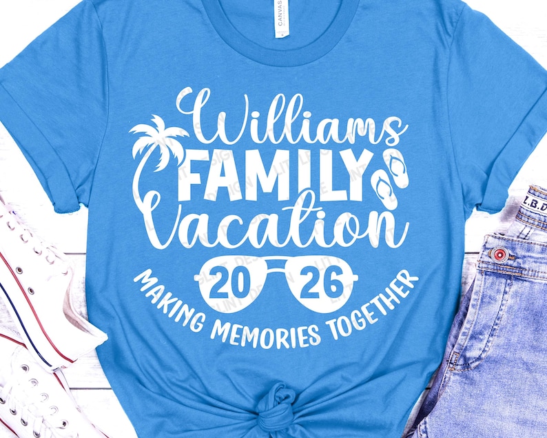 May include: A light blue t-shirt with the text "Williams FAMILY Vacation 2026 MAKING MEMORIES TOGETHER" in white. The design includes a palm tree, sunglasses, and flip-flops. The shirt is made of a soft material.