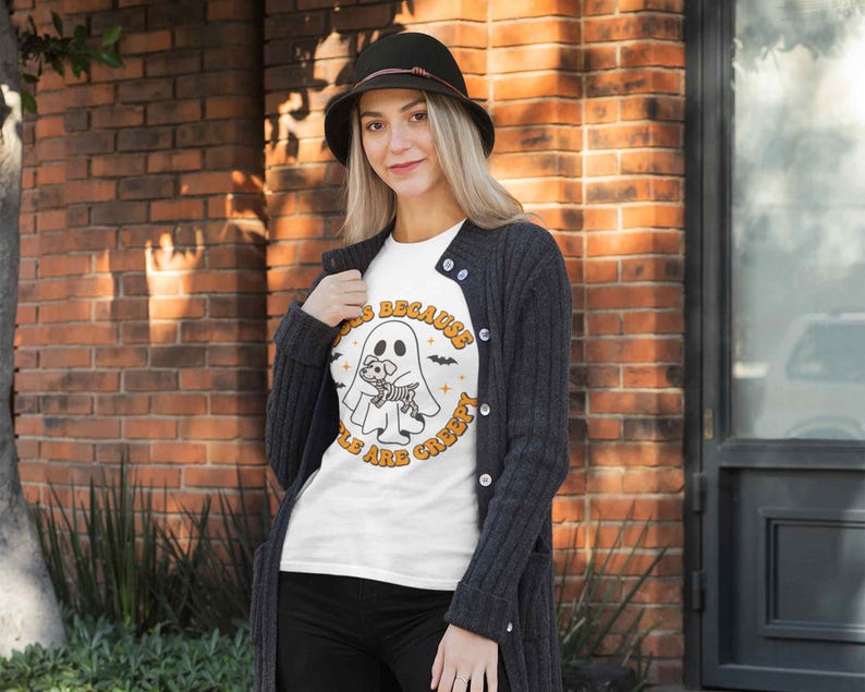May include: White t-shirt with a graphic of a ghost holding a skeleton dog. The text on the shirt reads "Dogs because people are creepy".