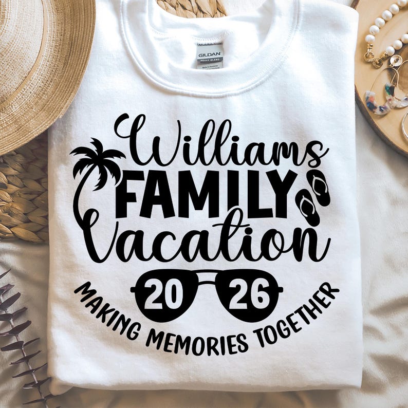 May include: White crew neck sweatshirt with the text "Williams FAMILY Vacation 2026 MAKING MEMORIES TOGETHER" in black. The design includes a palm tree, sunglasses, and flip-flops.
