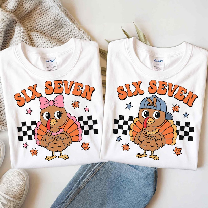 Pu&ograve; includere: Due magliette bianche con la scritta "SIX SEVEN" in arancione. Una maglietta presenta un tacchino dei cartoni animati con un fiocco rosa, l'altra un tacchino con un berretto blu. Entrambe hanno bandiere a scacchi, stelle e foglie d'autunno.