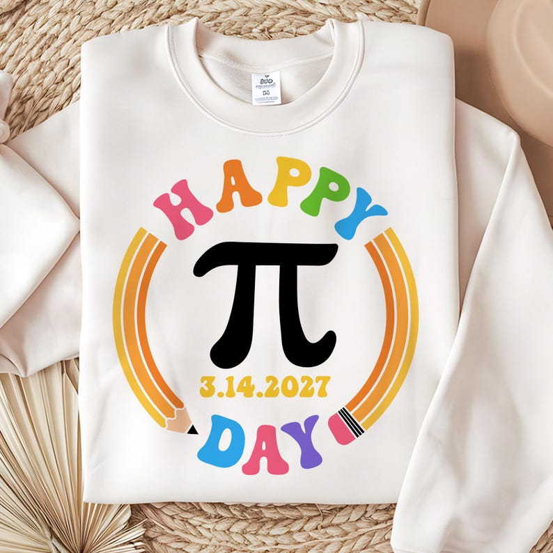Może przedstawiać: Biała bluza z kolorowym wzorem "Happy Pi Day". Wz&oacute;r zawiera czarny symbol pi, datę 3.14.2027 oraz tęczowy okrąg z oł&oacute;wkami. Tekst jest w r&oacute;żnych kolorach.