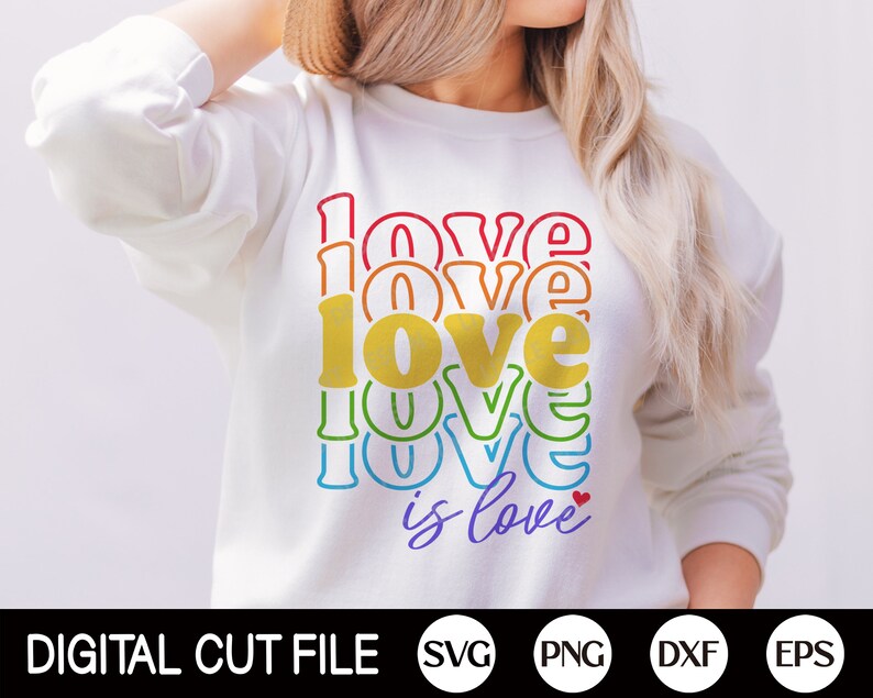 Puede incluir: Una sudadera blanca con un gr&aacute;fico de colores arco&iacute;ris que dice "love is love" con un peque&ntilde;o coraz&oacute;n rojo.