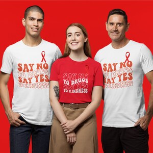 May include: Three white t-shirts with a red ribbon and the text "SAY NO TO DRUGS SAY YES TO KINDNESS" in a retro font. One t-shirt is red.