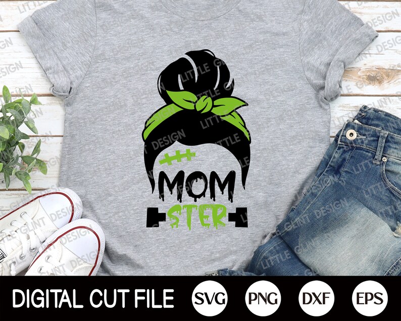 May include: A grey t-shirt featuring a black and green design of a woman's hair in a bun with a green headband. The text "Momster" is written below the hair design.