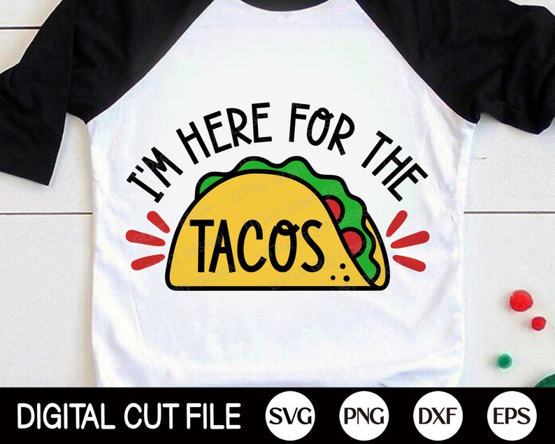 Puede incluir: Camiseta de estilo ragl&aacute;n blanca y negra con el texto "I'M HERE FOR THE TACOS" sobre un gr&aacute;fico de taco amarillo con lechuga verde y tomates rojos. La parte inferior de la camiseta tiene el texto "DIGITAL CUT FILE" e iconos de tipo de archivo.