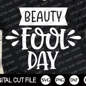 Op de afbeelding: Een zwart T-shirt met witte tekst die "Beauty Fool Day" luidt. De tekst is in een gestileerd lettertype en heeft een speelse uitstraling. Het shirt is een digitaal snijbestand en is beschikbaar in de formaten SVG, PNG, DXF en EPS.
