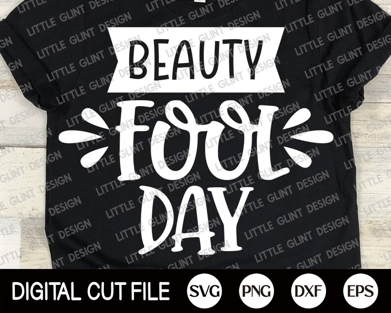 Op de afbeelding: Een zwart T-shirt met witte tekst die "Beauty Fool Day" luidt. De tekst is in een gestileerd lettertype en heeft een speelse uitstraling. Het shirt is een digitaal snijbestand en is beschikbaar in de formaten SVG, PNG, DXF en EPS.