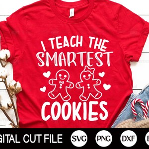 May include: A red t-shirt with the text "I TEACH THE SMARTEST COOKIES" in white. The design includes gingerbread people and hearts. Below the shirt is the text "DIGITAL CUT FILE" and file type icons.