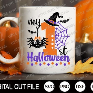 May include: White ceramic mug featuring a design of a spider, a witch's hat, and the text "my 1st Halloween". The design is in orange, purple, and black.