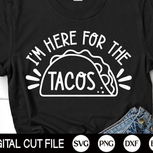 Puede incluir: Camiseta negra con un gr&aacute;fico blanco que dice "I'M HERE FOR THE TACOS" encima de una ilustraci&oacute;n de taco. La parte inferior de la camiseta muestra una porci&oacute;n de jeans azules. Las palabras "DIGITAL CUT FILE" est&aacute;n en la parte inferior.