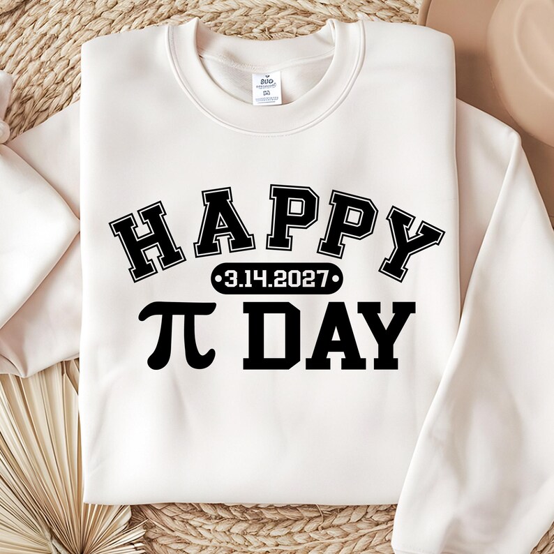 Pu&ograve; includere: Felpa color crema con le parole "HAPPY" e "&pi; DAY" in grassetto nero, in stile collegiale. La data "3.14.2027" &egrave; centrata tra le parole. La felpa &egrave; realizzata in un materiale morbido.