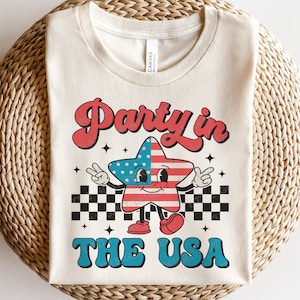 May include: A white t-shirt with a retro-style graphic of a cartoon star wearing a US flag design. The text "Party in the USA" is printed in blue and red letters.