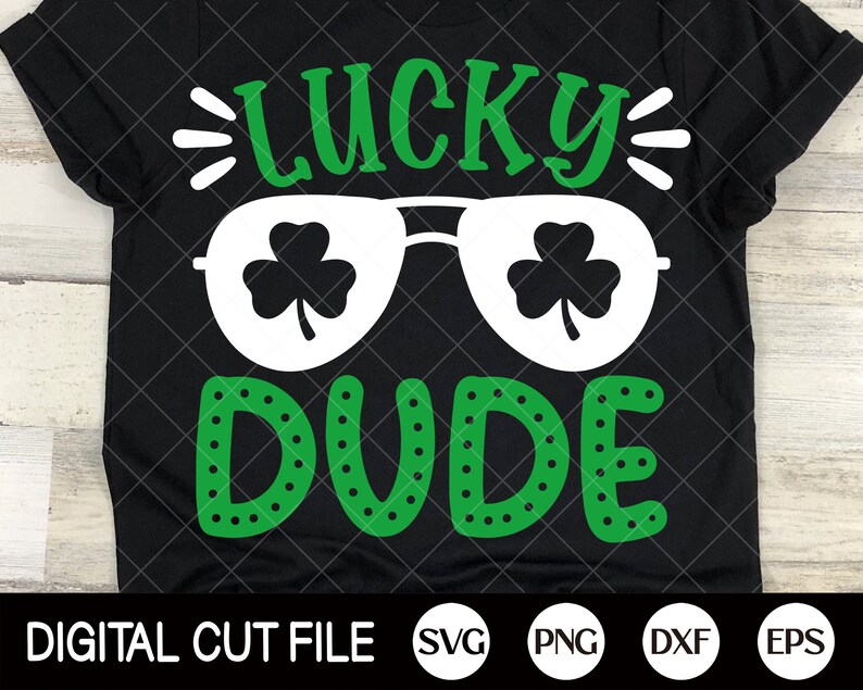 Może przedstawiać: Czarny T-shirt z zielonym wzorem koniczyny i tekstem "Lucky Dude" w kolorze białym. Koniczyny znajdują się wewnątrz białych okular&oacute;w przeciwsłonecznych.