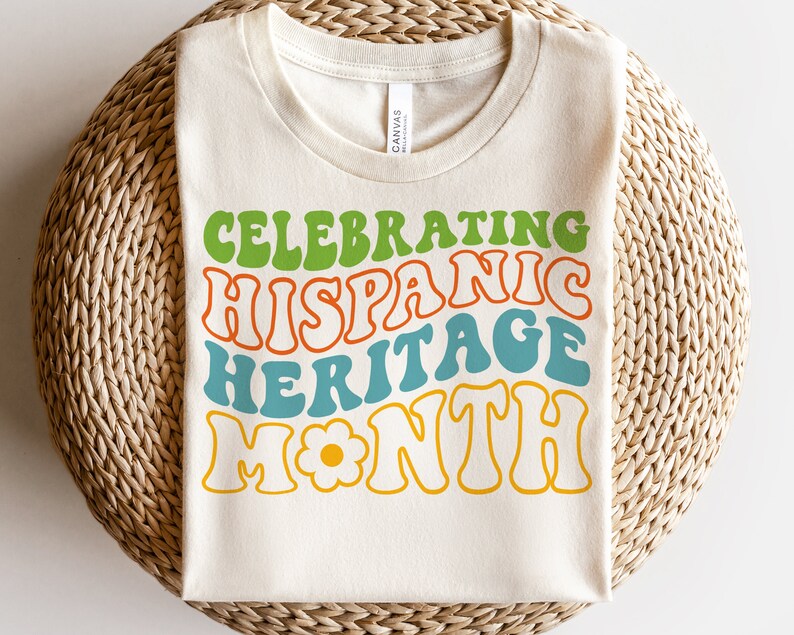May include: A white t-shirt with the text "Celebrating Hispanic Heritage Month" in a retro, colorful font. The text is in green, orange, blue, and yellow.