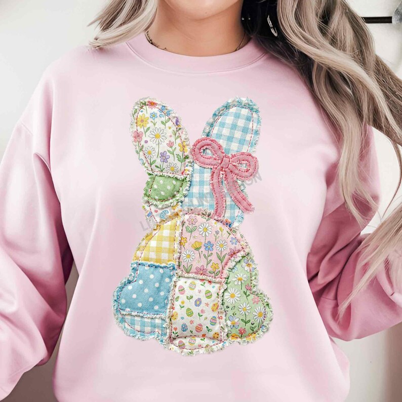 May include: A light pink sweatshirt featuring a patchwork bunny design. The bunny is composed of various fabric patterns, including floral, gingham, and polka dots, with a pink bow. The design is centered on the front of the sweatshirt.