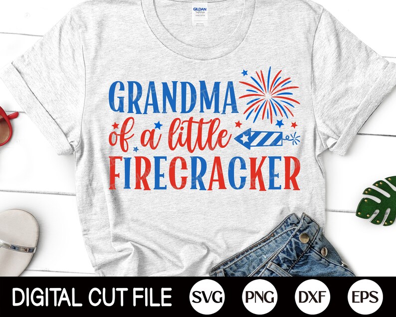 May include: A white t-shirt with the text "Grandma of a little Firecracker" in red and blue. The text is surrounded by red, white, and blue stars and a firework graphic.
