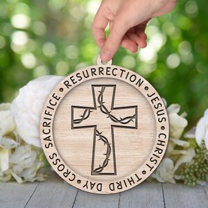 May include: A wooden round ornament with a cross design and the text "Third Day Cross Sacrifice Resurrection Jesus Christ" around the edge.