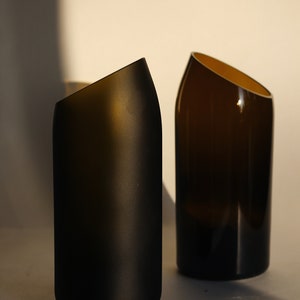 Pu&ograve; includere: Due vasi in vetro marrone scuro con un design angolare unico. Il vaso a sinistra &egrave; smerigliato, mentre il vaso a destra &egrave; trasparente.