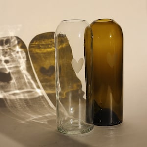 May include: Two glass vases, one clear and one brown, with a heart etched into the front of each.