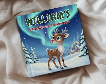 May include: A children's book titled "WILLIAM'S Christmas Adventure" featuring a cartoon reindeer with a red nose. The cover art depicts a snowy winter scene with a house, trees, and aurora borealis in the background. The book is set on a white blanket.