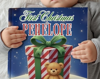 May include: A children's book titled "First Christmas for Penelope" featuring a gift box with a green bow and a teddy bear. The book has a blue background with stars.