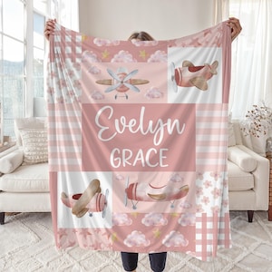 May include: Pink and white baby blanket with a patchwork design featuring airplanes, clouds, stars, and gingham patterns. The blanket is personalized with the name "Evelyn Grace".