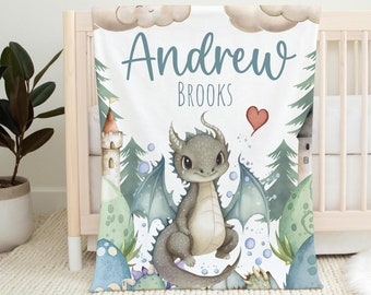 May include: A white baby blanket with a watercolor illustration of a green dragon with blue wings. The blanket has the name "Andrew Brooks" written in blue text.