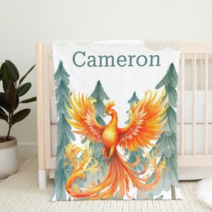 May include: Personalized baby blanket with a white background featuring a watercolor illustration of a phoenix in a forest setting. The name "Cameron" is written in teal green text at the top of the blanket.