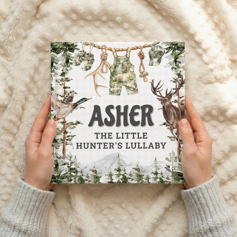 May include: A children's book titled "Asher The Little Hunter's Lullaby" with illustrations of hunting-themed items. The cover features a duck, deer, and camouflage overalls. The book is held by a person.