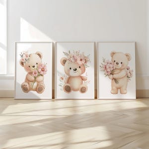 May include: Three framed watercolor prints featuring adorable teddy bears. Each bear is depicted in soft, pastel colors, adorned with floral accents, and holding or wearing flowers. The artwork is set against a white background, creating a charming and whimsical aesthetic.